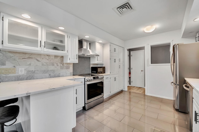 kitchen with white cabinets, decorative backsplash, wall chimney range hood, and stainless steel appliances