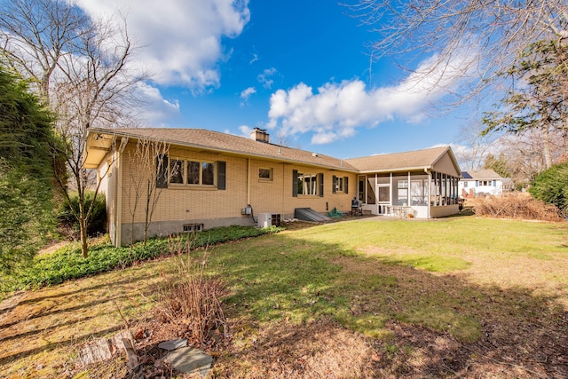 rear view of house featuring a lawn and a sunroom