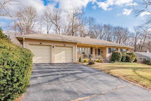 single story home with covered porch, a garage, and a front lawn