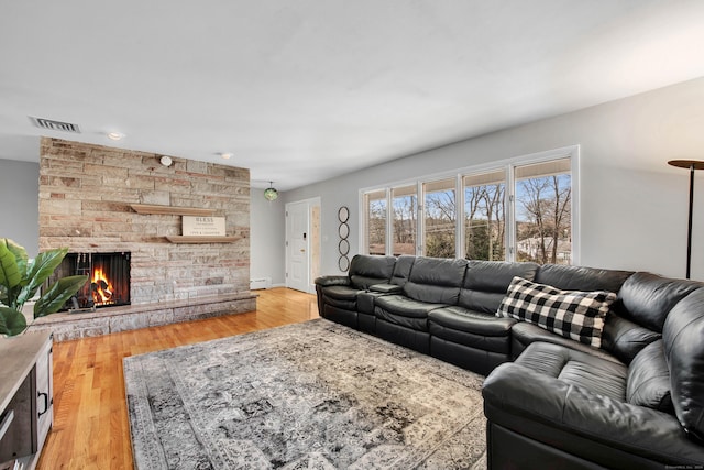 living room featuring light hardwood / wood-style floors, baseboard heating, and a fireplace