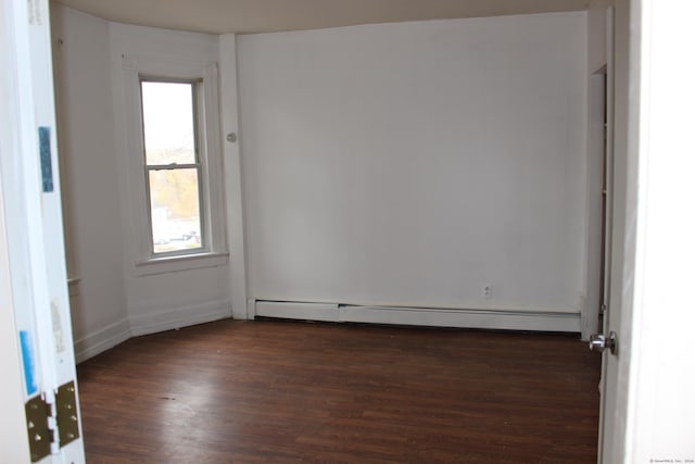 spare room with dark hardwood / wood-style flooring and a baseboard heating unit