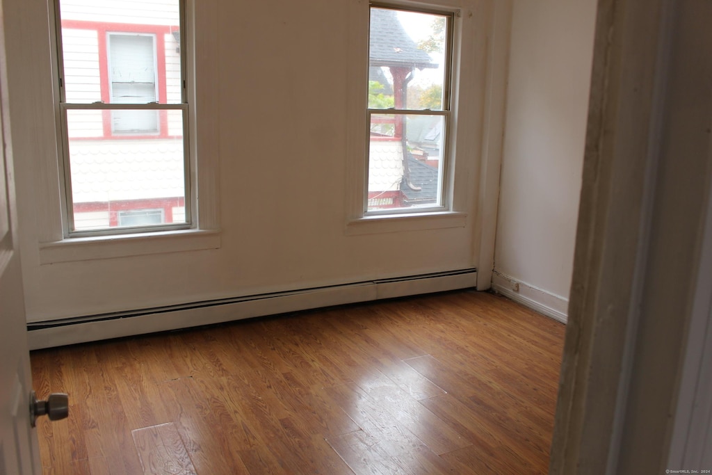 empty room featuring light wood-type flooring and a baseboard radiator