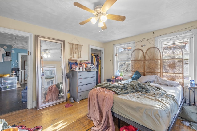 bedroom with multiple windows, wood-type flooring, a closet, and ceiling fan