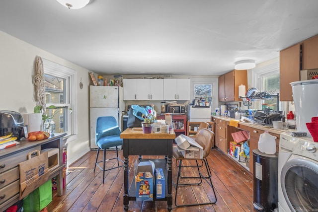 kitchen with washer / dryer, white fridge, white cabinetry, and dark hardwood / wood-style floors