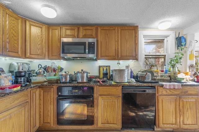 kitchen featuring black appliances, a textured ceiling, and dark stone counters