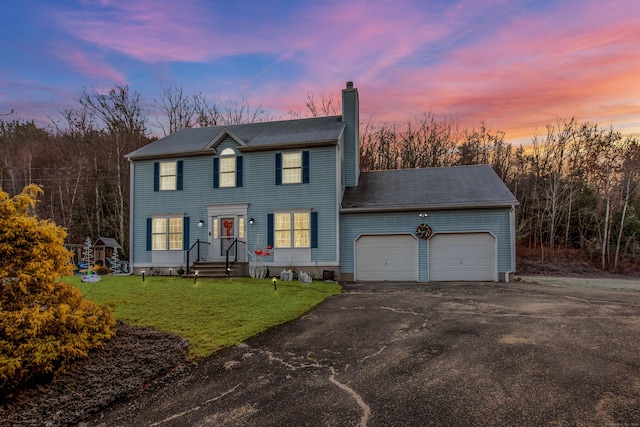 colonial-style house featuring a yard and a garage