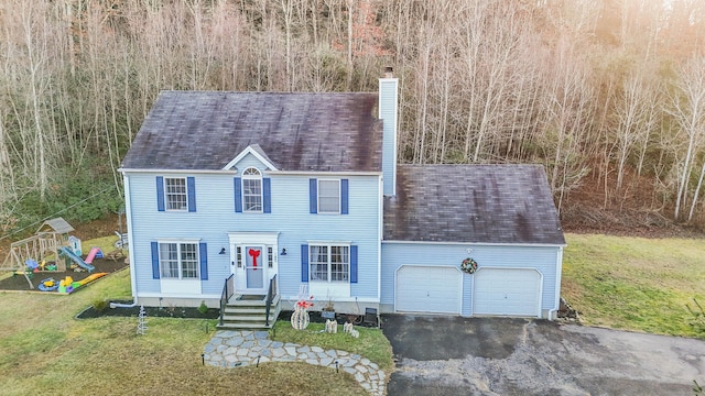 colonial house with a garage, a playground, and a front yard