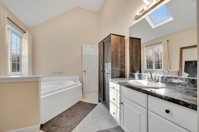 bathroom with lofted ceiling with skylight, vanity, a healthy amount of sunlight, and a relaxing tiled tub