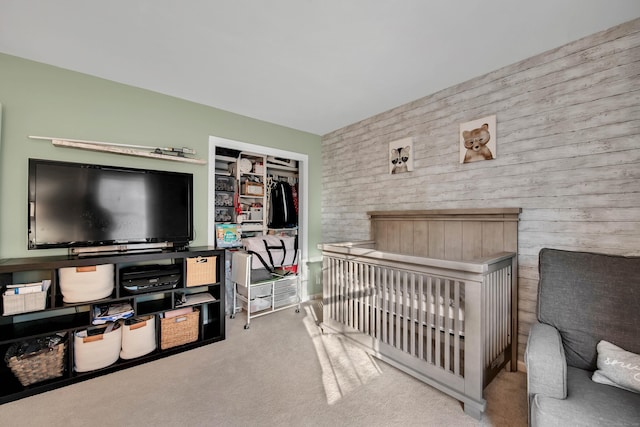 bedroom with a closet, light colored carpet, and a crib