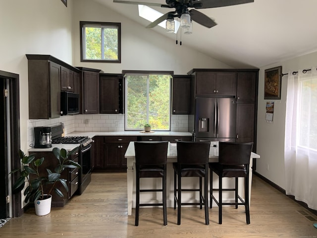 kitchen featuring stainless steel appliances, a center island, tasteful backsplash, a kitchen bar, and light wood-type flooring