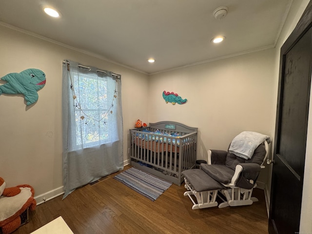 bedroom featuring dark wood-type flooring, ornamental molding, and a nursery area