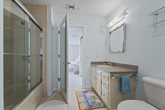 full bathroom featuring vanity, tile patterned floors, combined bath / shower with glass door, toilet, and a textured ceiling