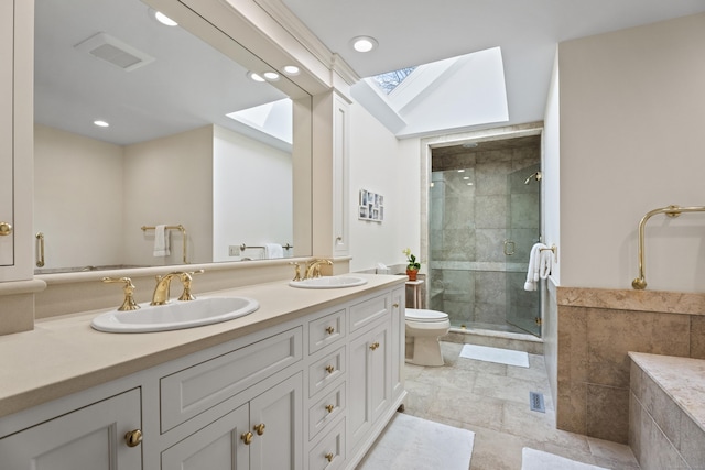 bathroom with vanity, a skylight, toilet, and a shower with door