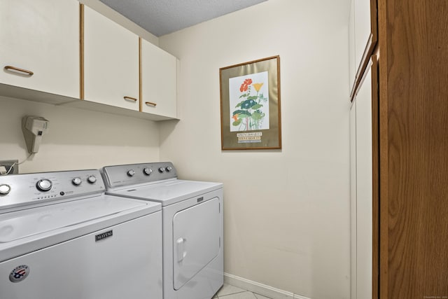 clothes washing area with light tile patterned floors, cabinets, a textured ceiling, and independent washer and dryer