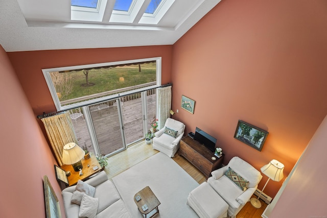 living room featuring hardwood / wood-style flooring, baseboard heating, and lofted ceiling