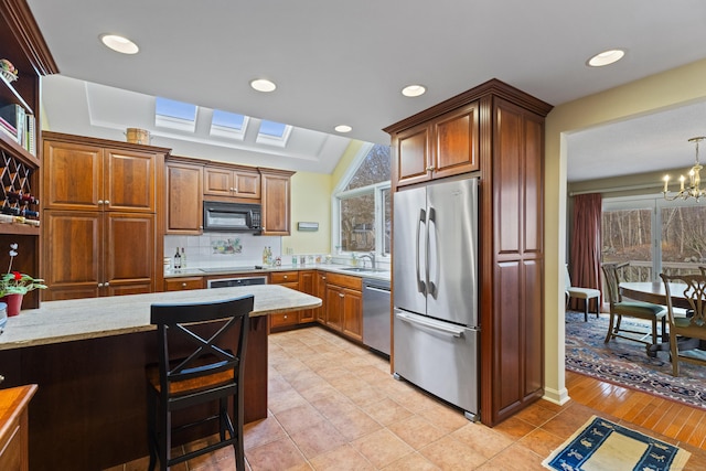 kitchen with sink, a chandelier, pendant lighting, decorative backsplash, and appliances with stainless steel finishes