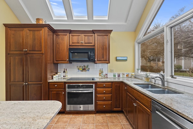 kitchen featuring black appliances, tasteful backsplash, sink, and a skylight