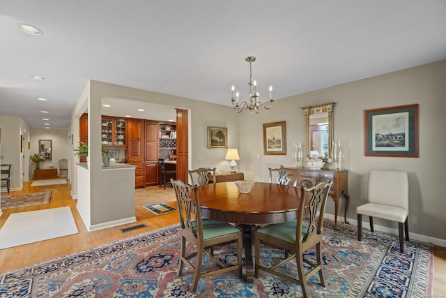 dining space featuring light wood-type flooring and an inviting chandelier