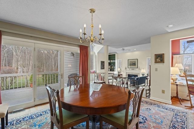 dining room featuring a textured ceiling, hardwood / wood-style floors, and ceiling fan with notable chandelier