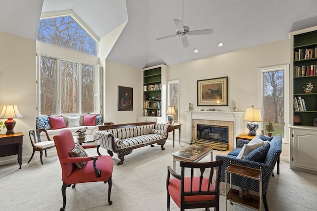 carpeted living room with high vaulted ceiling, ceiling fan, and a tiled fireplace