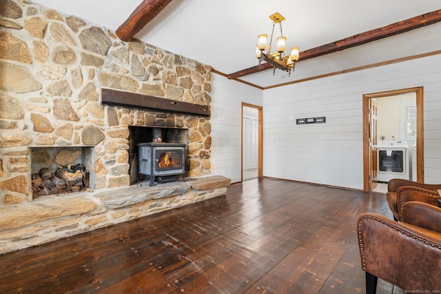 living room with dark wood-type flooring, beam ceiling, wooden walls, a chandelier, and a wood stove