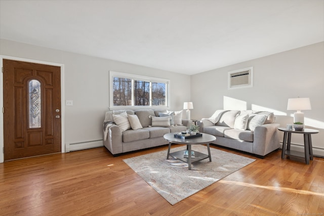 living room featuring a baseboard heating unit, an AC wall unit, and light wood finished floors