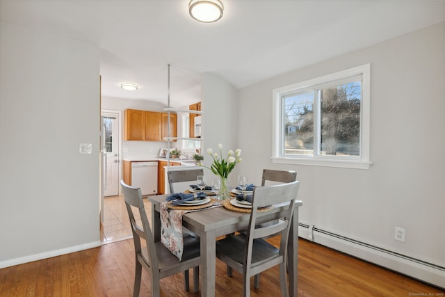 dining space featuring light wood-style flooring, plenty of natural light, baseboards, and baseboard heating