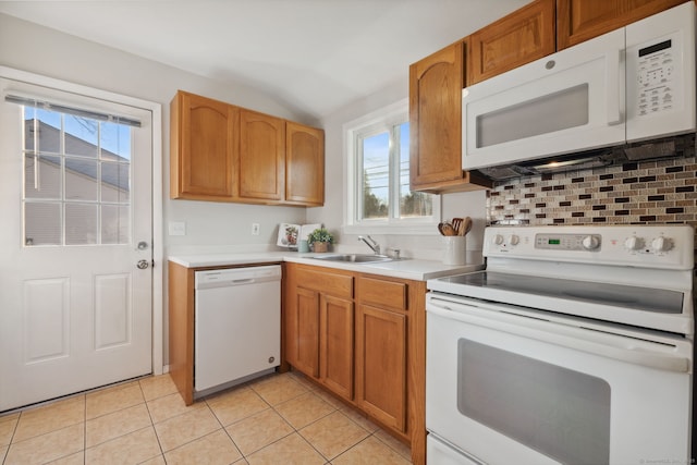 kitchen featuring white appliances, light tile patterned floors, a sink, light countertops, and tasteful backsplash