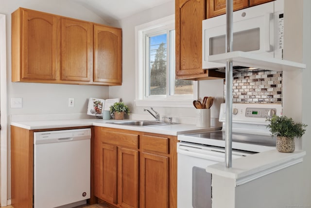 kitchen with a sink, white appliances, vaulted ceiling, and light countertops