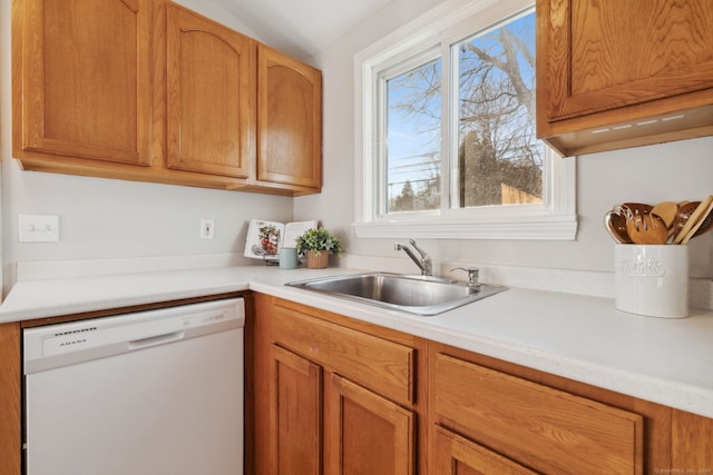 kitchen featuring brown cabinets, dishwasher, light countertops, and a sink