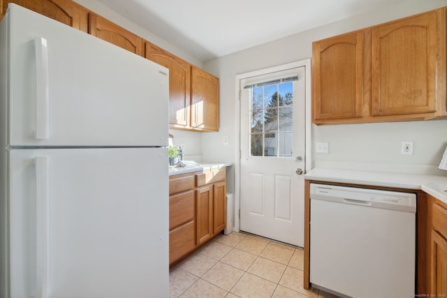 kitchen featuring light tile patterned flooring, brown cabinetry, white appliances, and light countertops