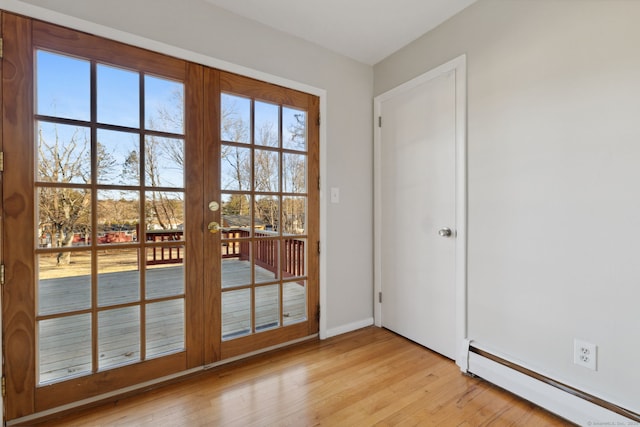 doorway with a baseboard heating unit, baseboards, and light wood finished floors