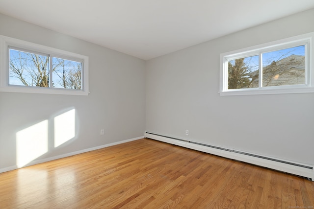 spare room with light wood-style flooring, a baseboard heating unit, and baseboards