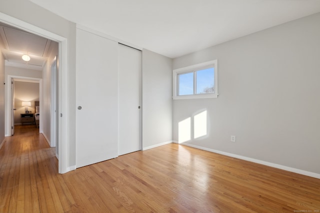 unfurnished bedroom featuring a closet, baseboards, and light wood-style flooring