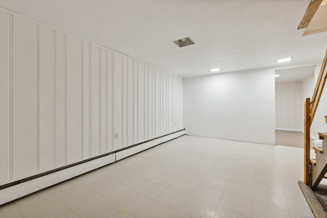 finished basement featuring stairway, light floors, and a baseboard radiator