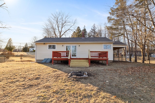 rear view of house featuring a deck, a carport, fence, and a chimney