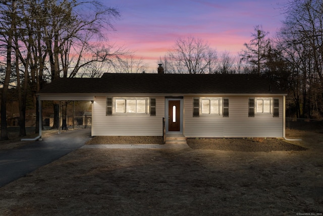 view of front of property with entry steps, aphalt driveway, roof with shingles, and a chimney