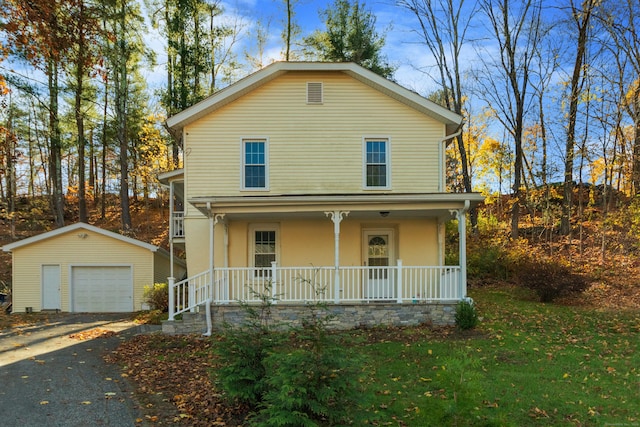 front facade with covered porch, a garage, a front lawn, and an outdoor structure