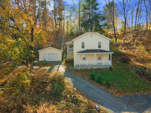 view of front of house with a porch, a garage, and an outbuilding