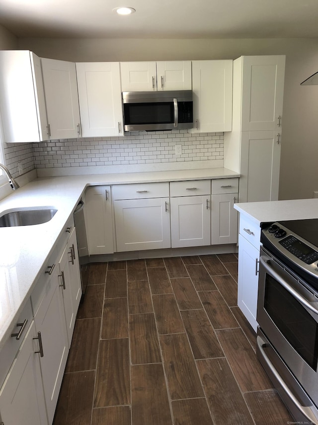 86 Vanguard St, Bridgeport, CT 06606 - kitchen with appliances with stainless steel finishes, recessed lighting, wood tiled floors, white cabinets, and tasteful backsplash