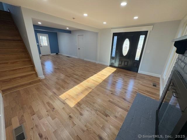 foyer with light hardwood / wood-style floors and a stone fireplace