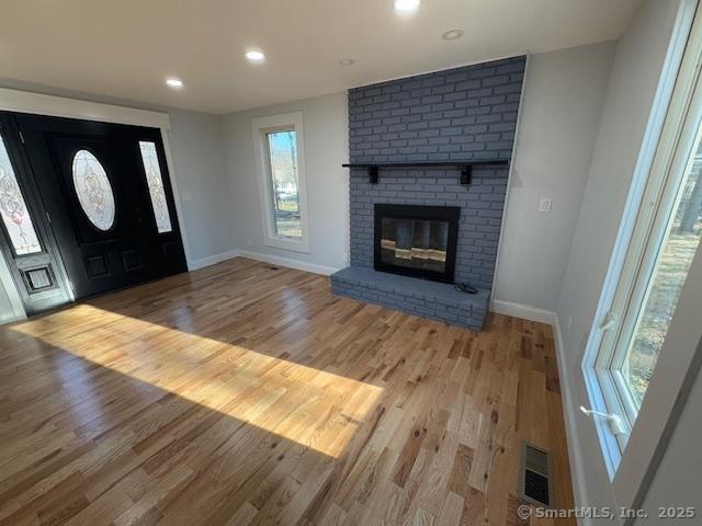 foyer entrance featuring light wood-type flooring and a fireplace