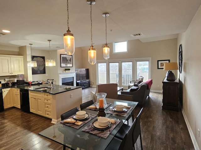 kitchen with dishwasher, sink, dark hardwood / wood-style floors, decorative light fixtures, and kitchen peninsula