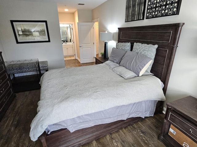 bedroom featuring ensuite bathroom and dark wood-type flooring