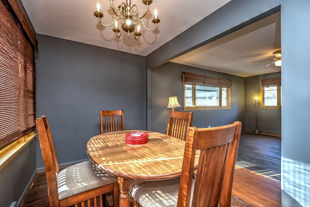 dining space with dark wood-type flooring and ceiling fan with notable chandelier