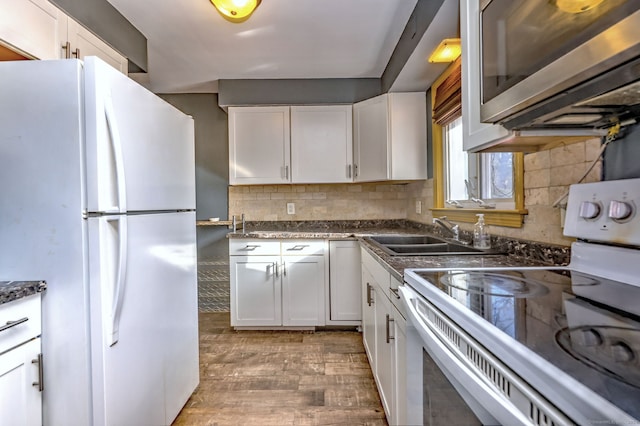 kitchen featuring decorative backsplash, white appliances, sink, hardwood / wood-style flooring, and white cabinets