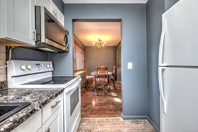 kitchen with white cabinetry, dark hardwood / wood-style floors, a notable chandelier, dark stone countertops, and white appliances