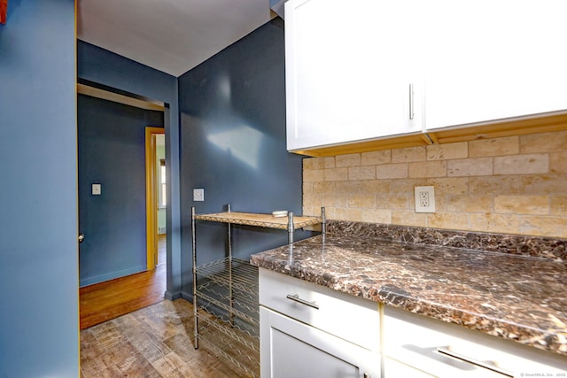 kitchen with decorative backsplash, white cabinetry, dark stone counters, and light hardwood / wood-style floors