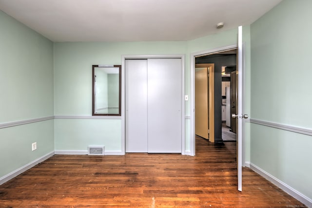 unfurnished bedroom featuring a closet and dark wood-type flooring