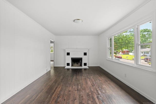 unfurnished living room featuring a healthy amount of sunlight, a brick fireplace, dark wood-type flooring, and crown molding